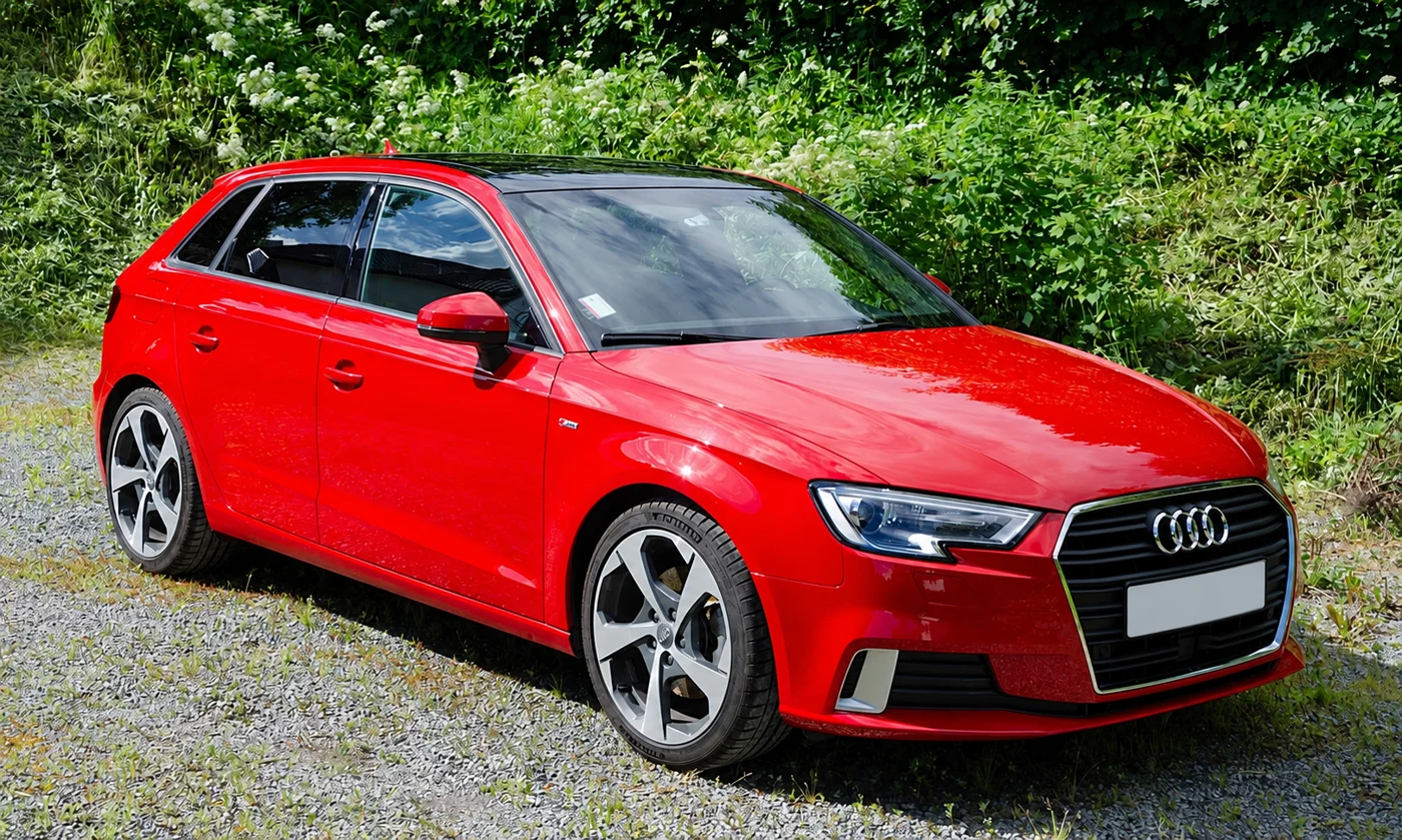 Audi A3 rojo en un camino de grava, fotografía referencial